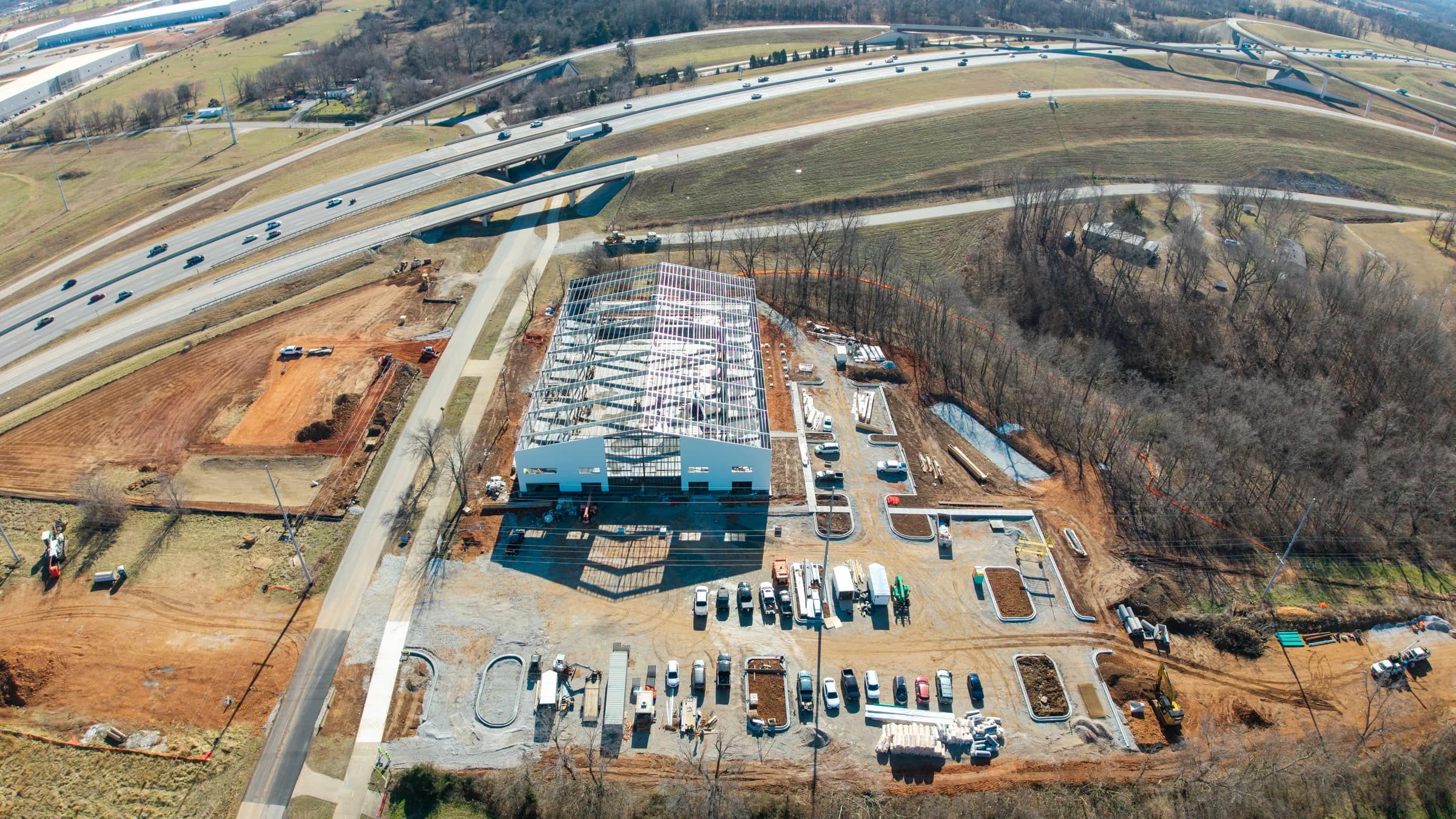 Aerial view of commercial construction site with steel framing near a highway interchange in Northwest Arkansas